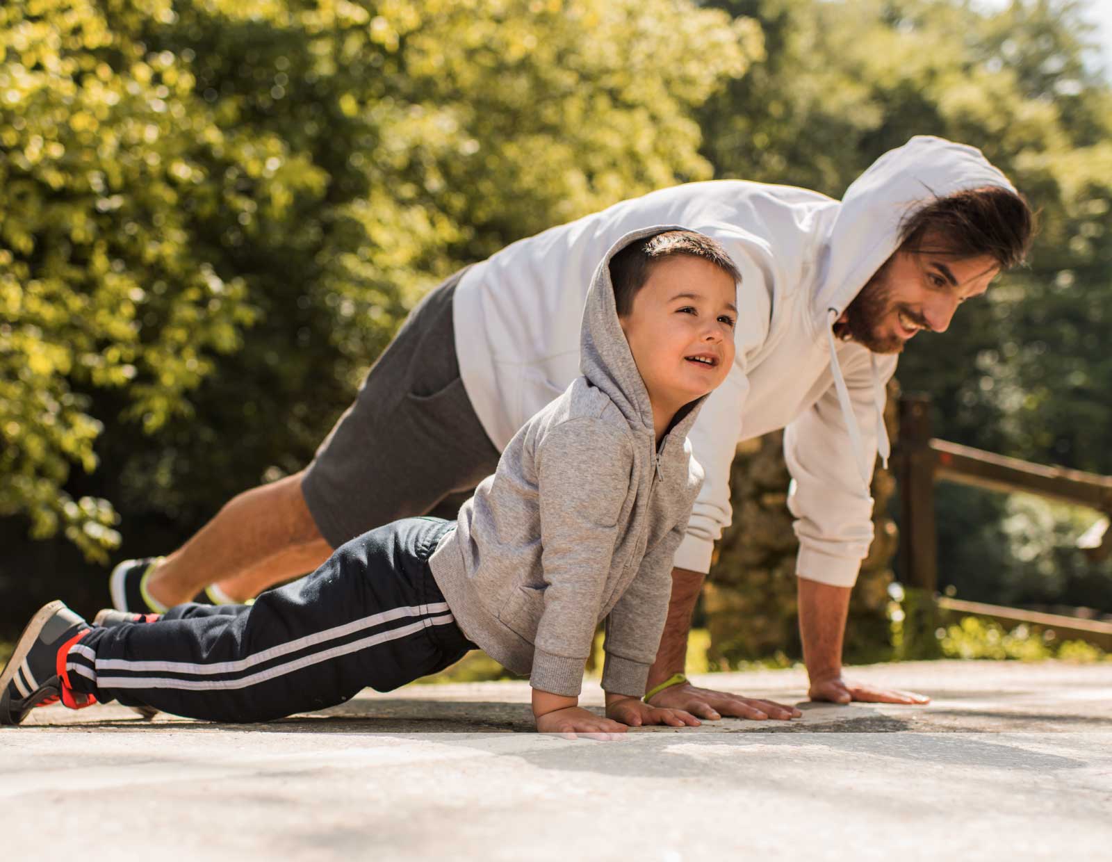 Vater und Sohn machen Sport im Freien und befinden sich in der Liegestütz-Position.